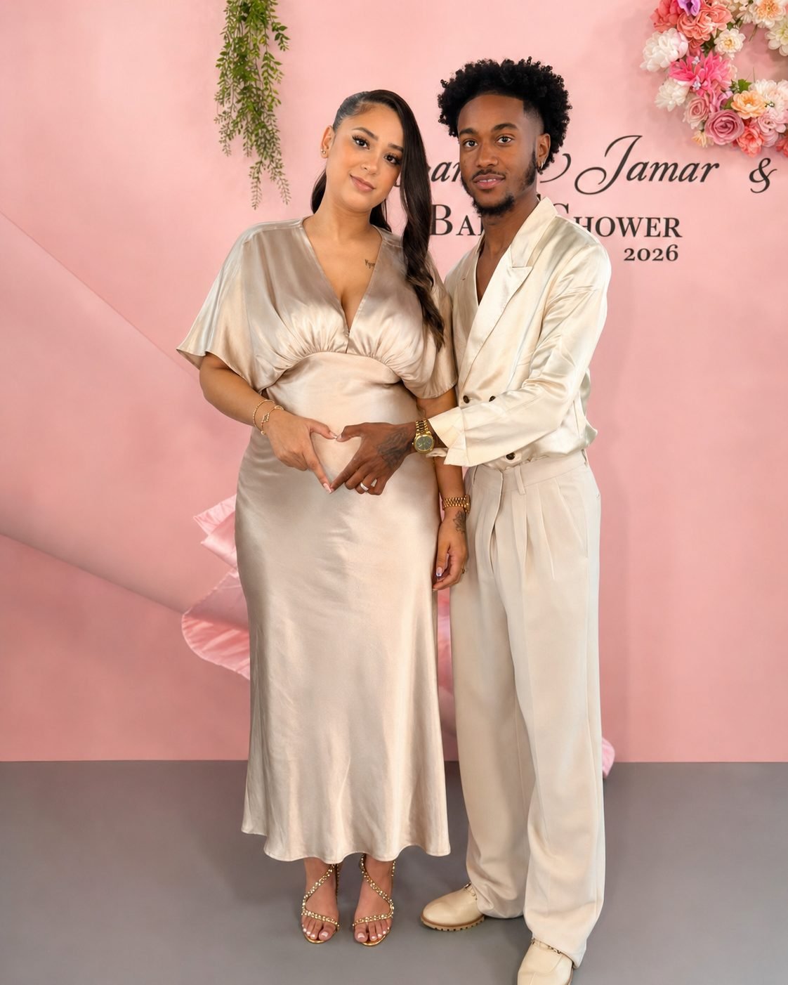 Expectant couple in front of a pink baby shower backdrop at The Hendrix in Stafford