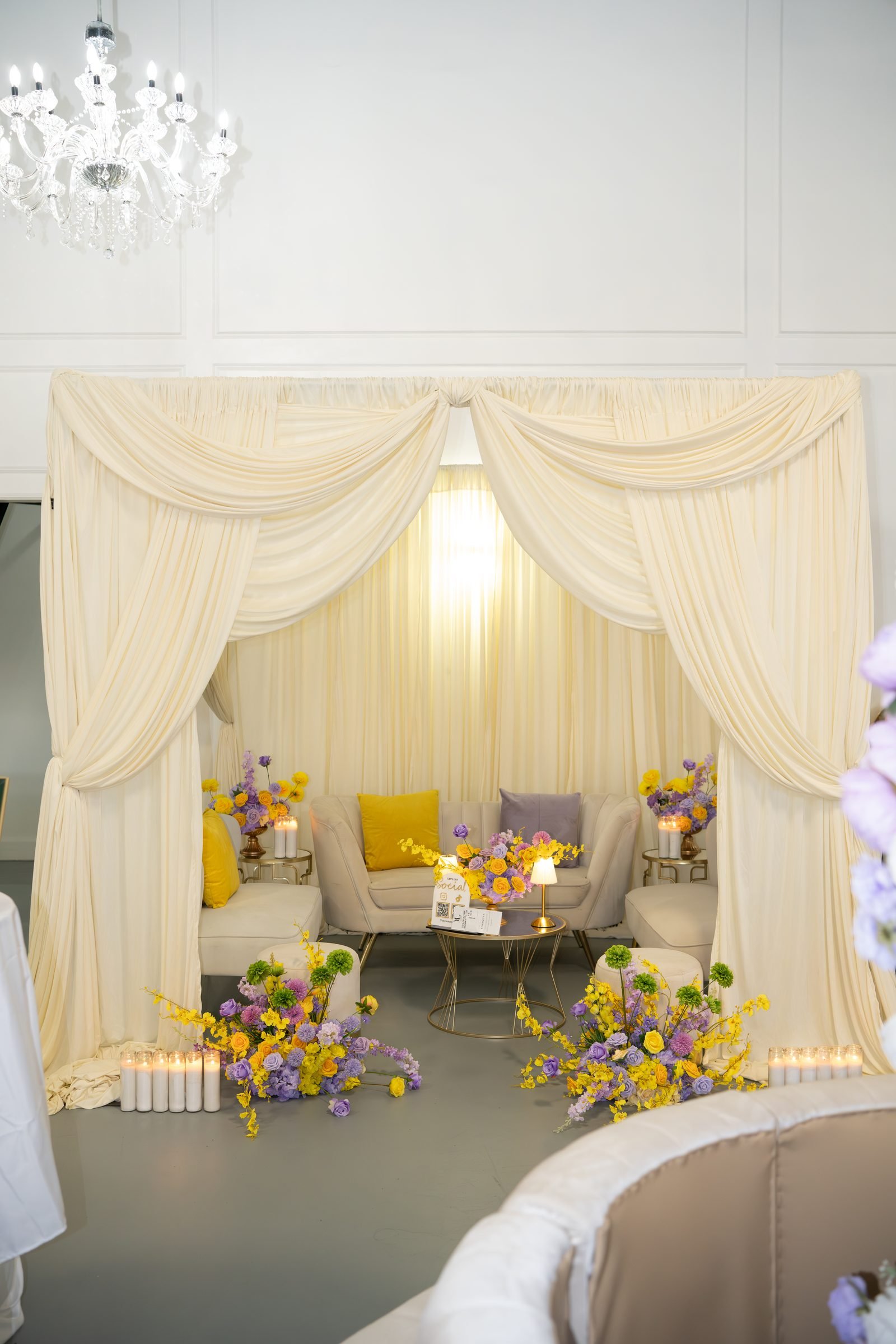 Draped lounge setting with chandelier and florals inside The Hendrix event venue in Stafford, Houston