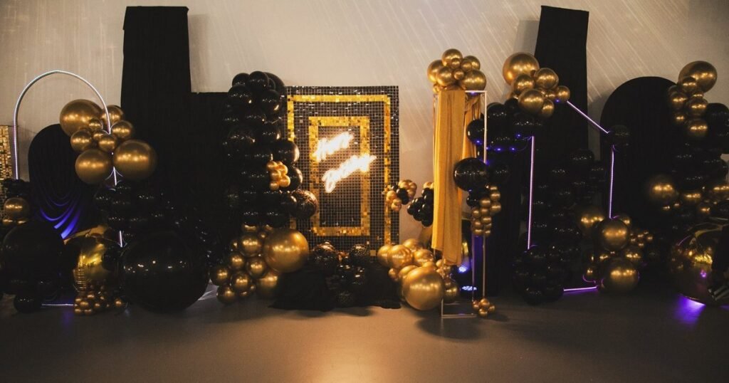 A black and gold balloon and sequin backdrop with a neon Happy Birthday sign at an adult birthday party at The Hendrix in Stafford, Houston