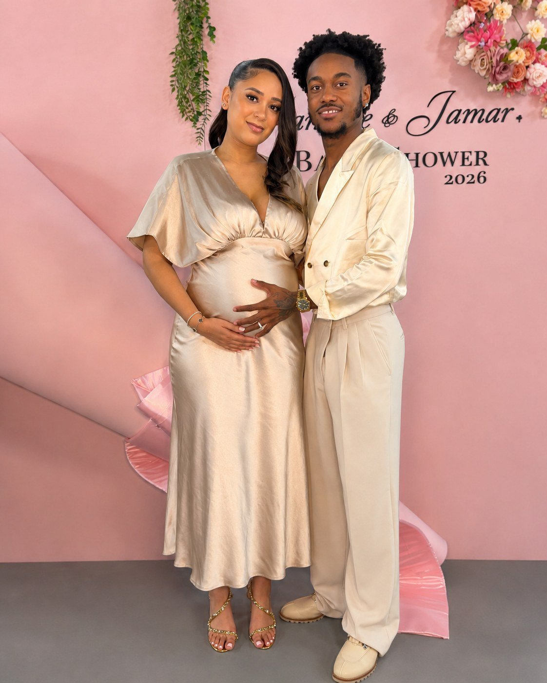 An expectant couple in front of a blush pink baby shower backdrop at The Hendrix, Stafford, Houston