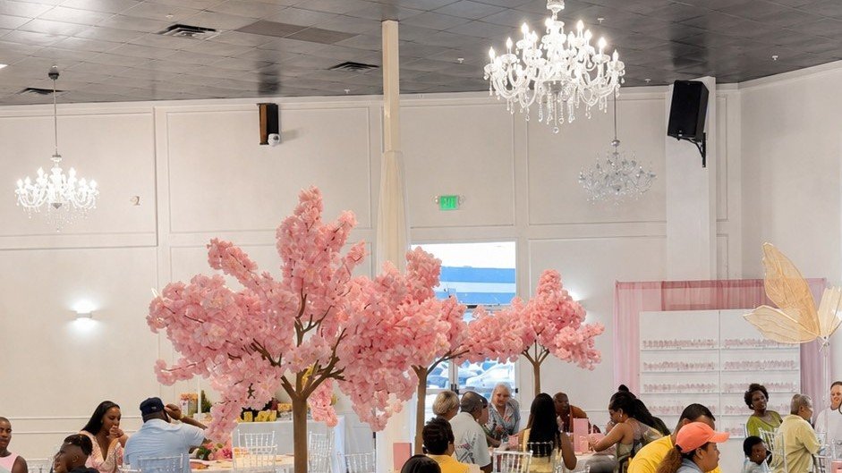 Guests seated among blossom trees beneath the chandeliers at a celebration in The Mansion at The Hendrix, Stafford