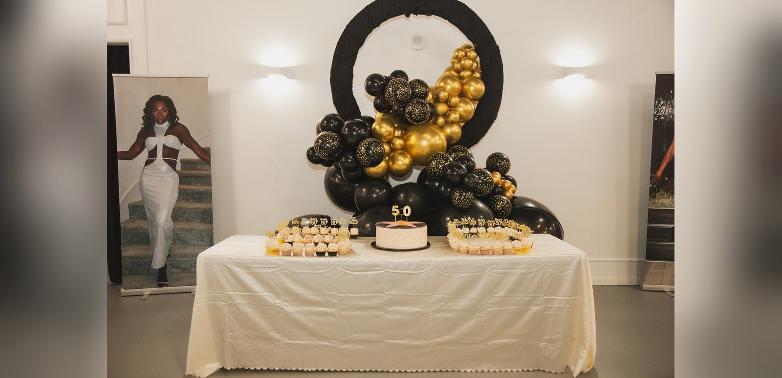A cake table beneath a black and gold balloon arch at a milestone birthday at The Hendrix, Stafford