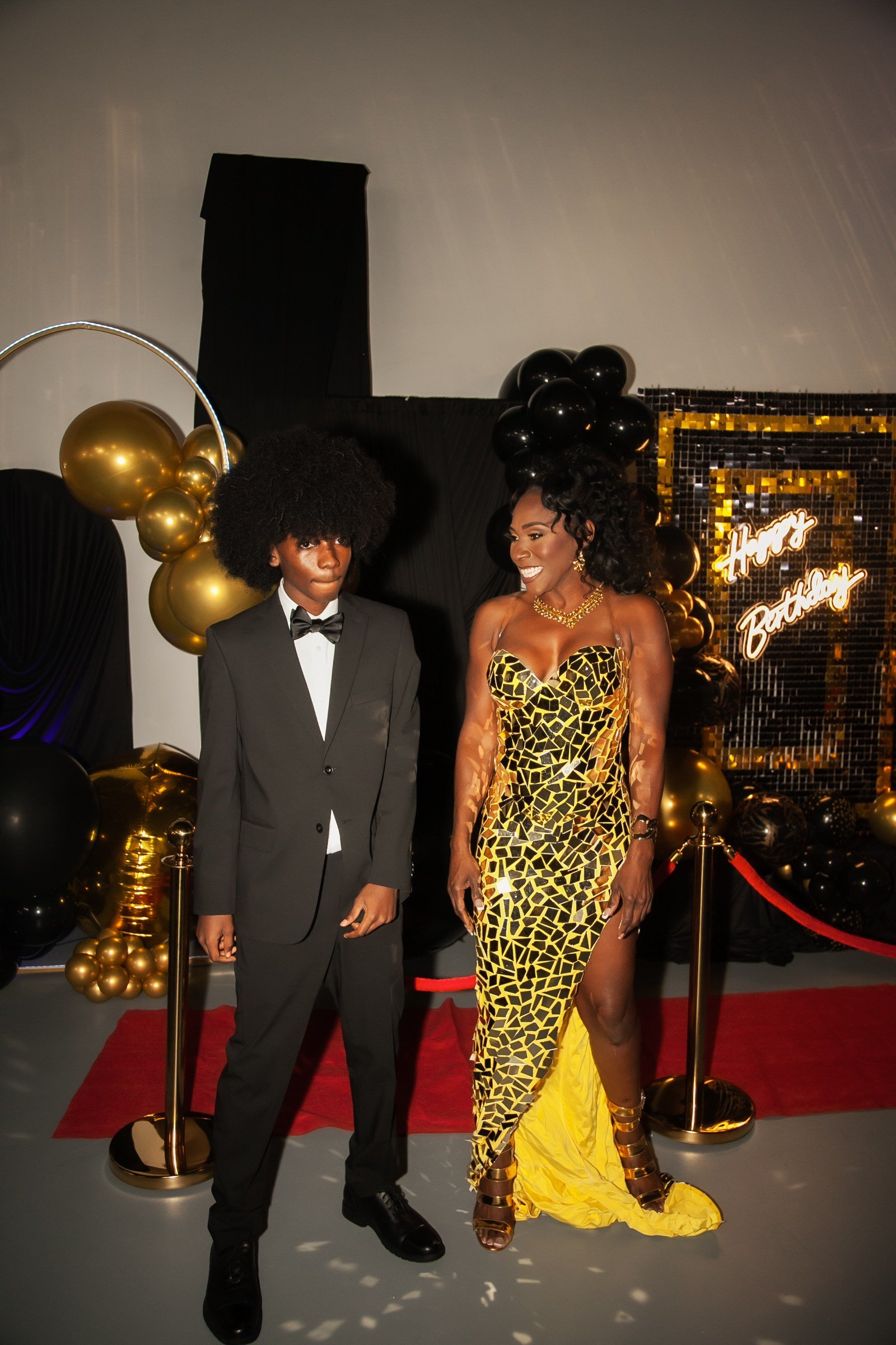 A couple in a tuxedo and gold gown on the red carpet at a 50th birthday at The Hendrix, Stafford