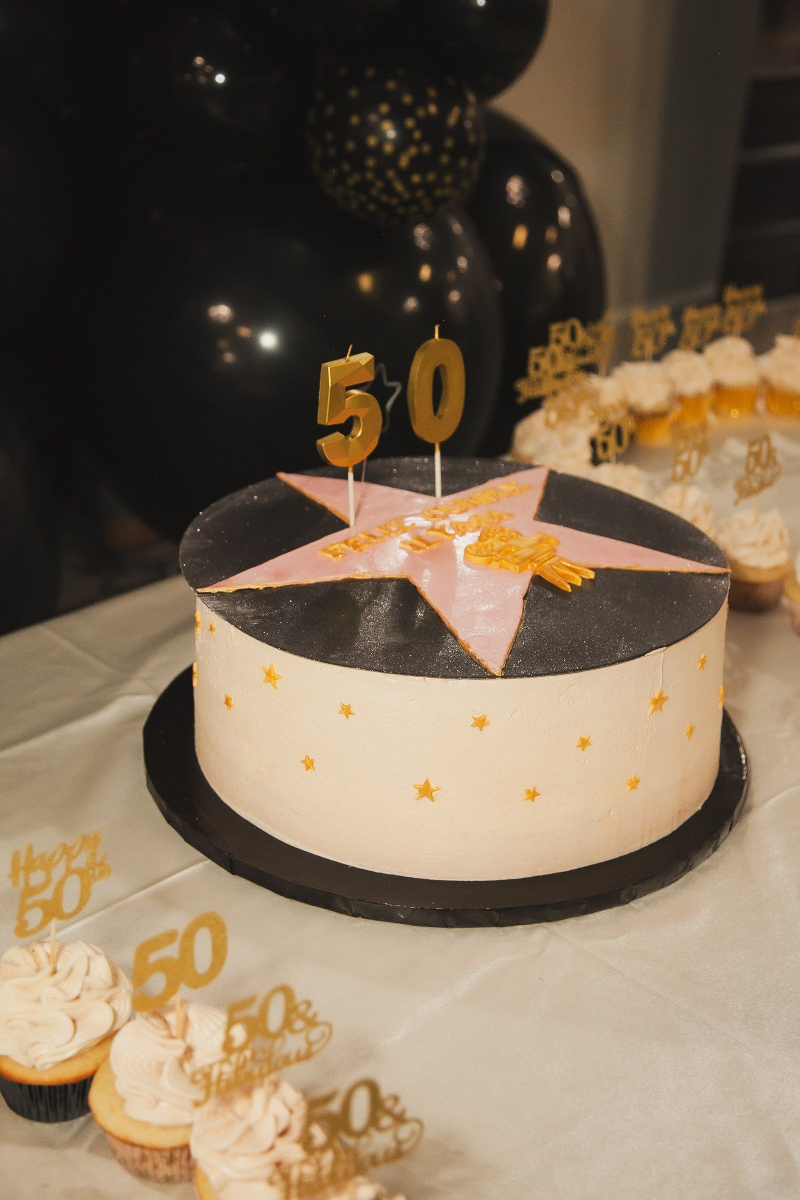 A gold and black 50th birthday cake with cupcakes at The Hendrix, Stafford, Houston