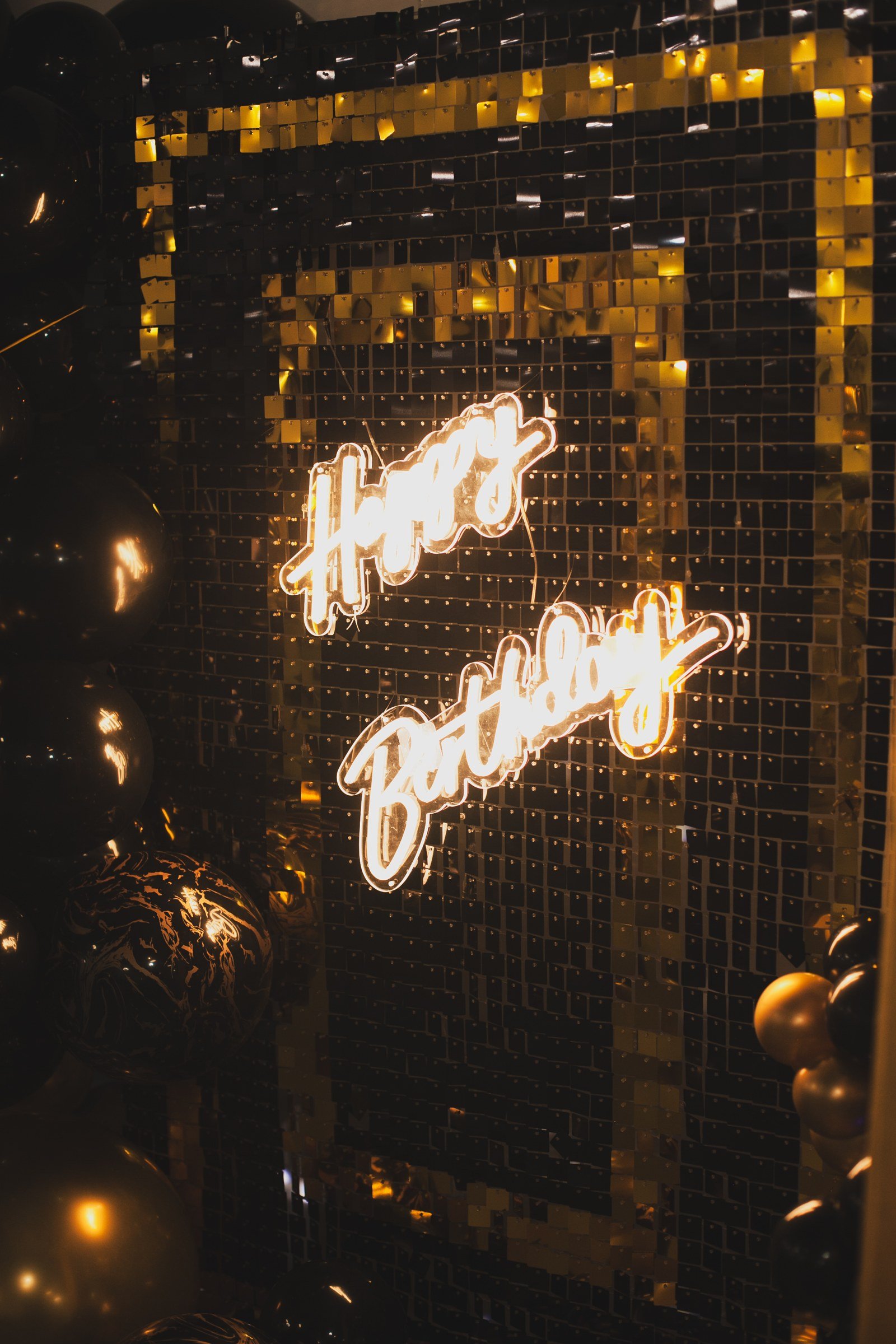 A gold sequin wall with a neon happy birthday sign at a milestone birthday at The Hendrix