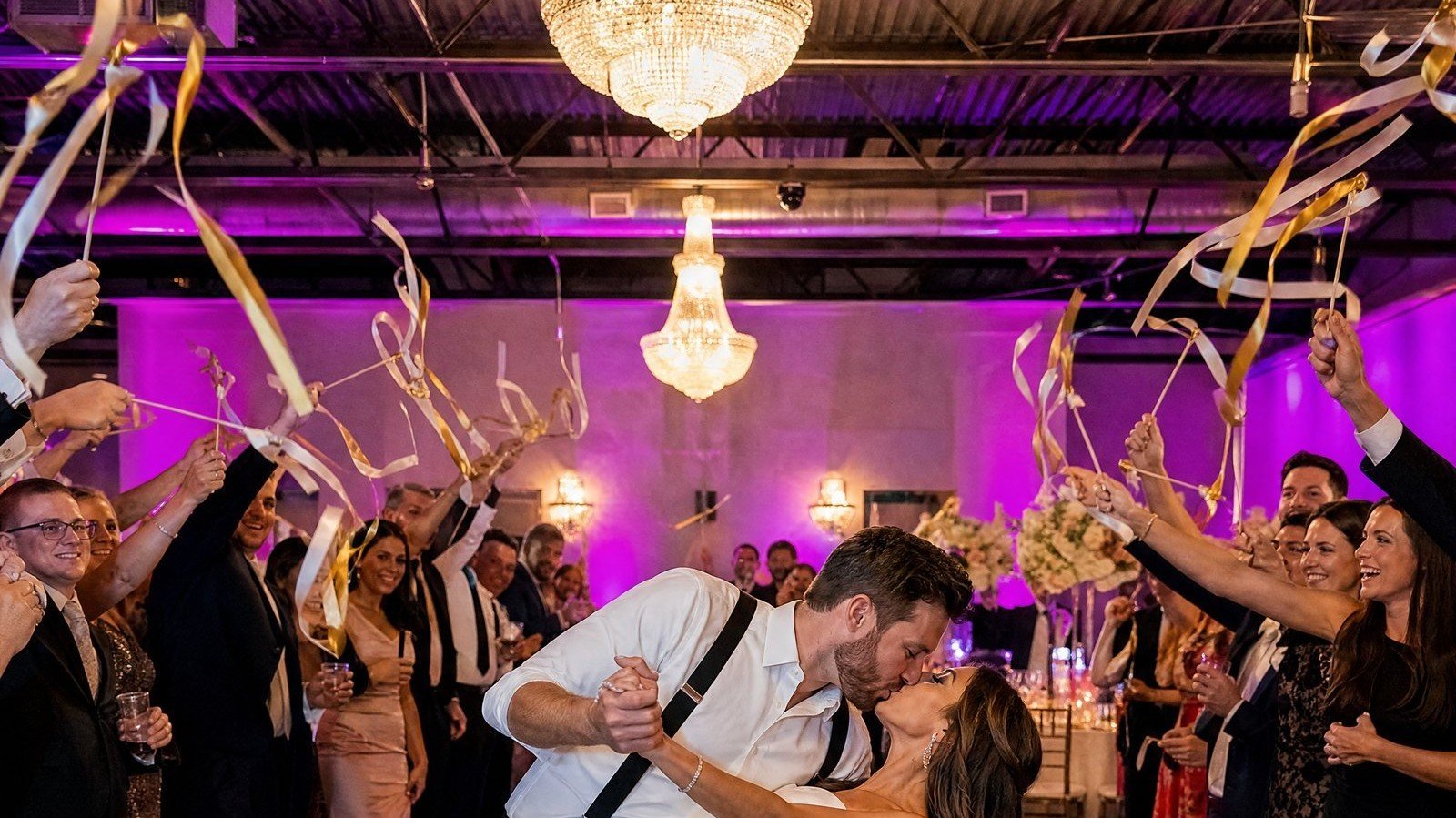 Newlyweds share a dip kiss as guests wave ribbon wands at The Hendrix, Stafford, Houston