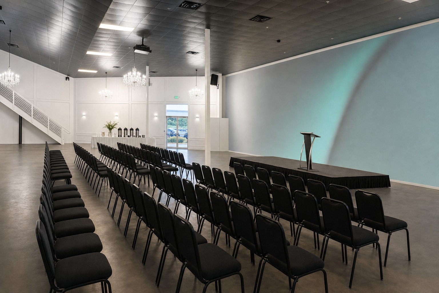 The Mansion at The Hendrix laid out theatre-style with rows of black chairs, a stage, a lectern and a coffee station at the back