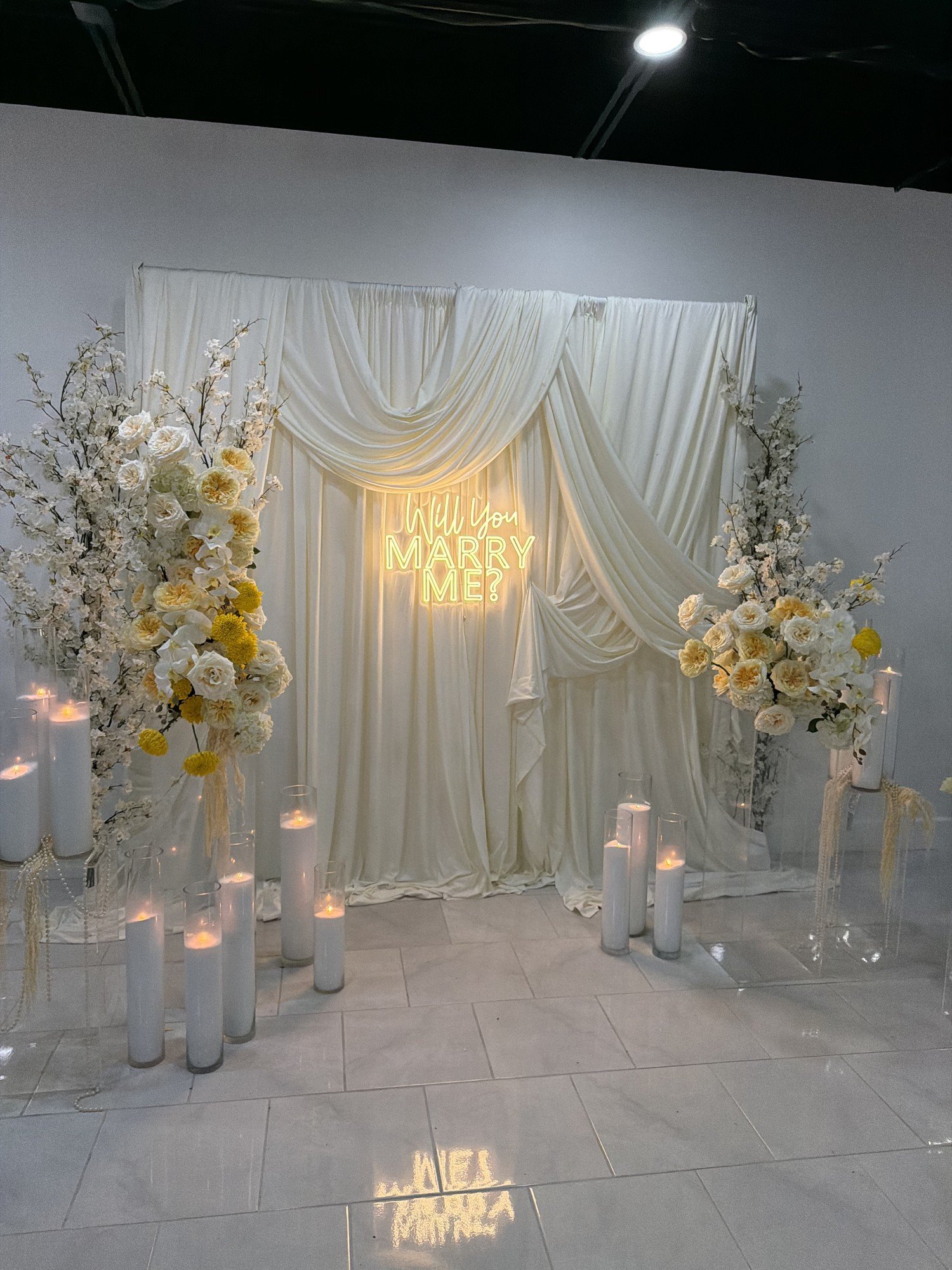 A candle-lined aisle leading to a draped proposal backdrop with florals at The Hendrix, Stafford