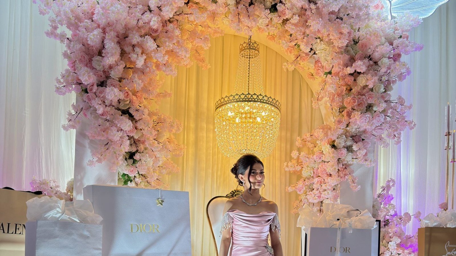 A quinceañera beneath a pink blossom arch at her celebration in The Hendrix, Stafford, Houston