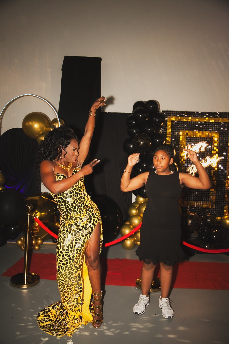 The celebrant dancing with a young guest in front of the neon backdrop at her 50th at The Hendrix