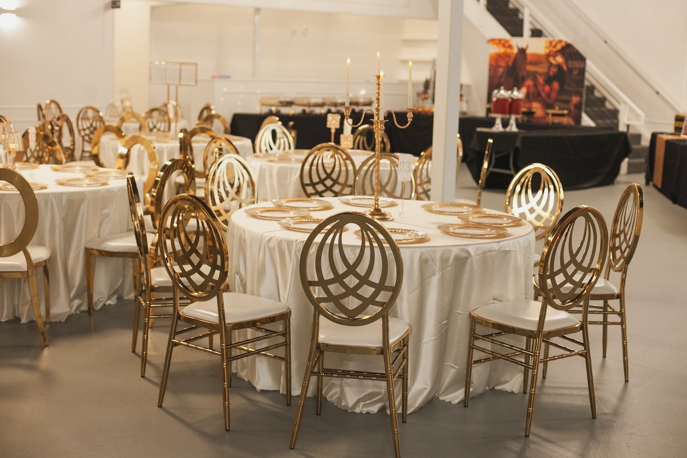 Round tables with ivory linens and gold Chiavari chairs set for a party in the Mansion at The Hendrix in Stafford