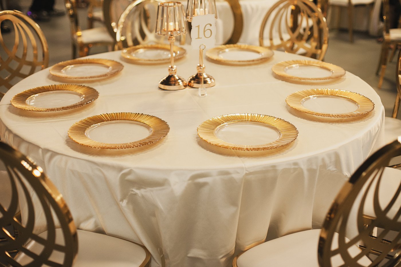 An ivory tablescape with gold rim chargers and a gold candelabra at The Hendrix