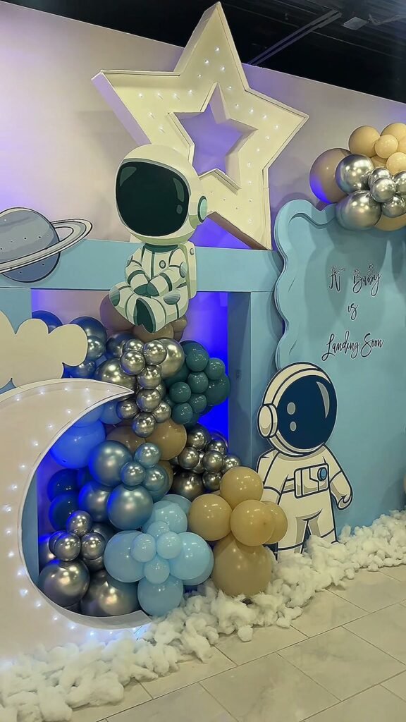 A moon and star backdrop with an astronaut and balloon garland at a baby shower in The Dome at The Hendrix