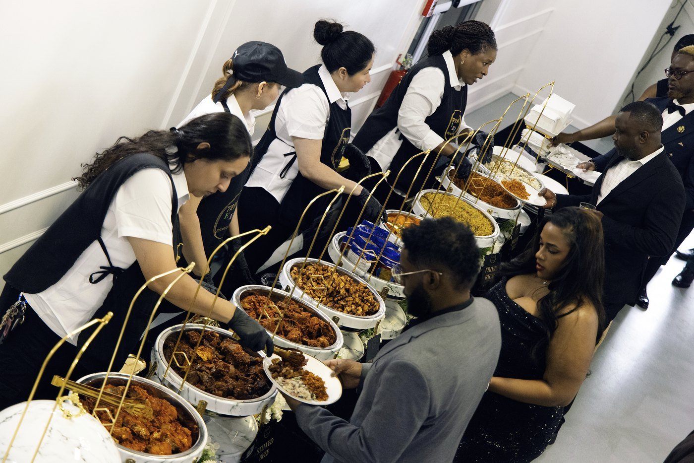 Servers plating from marble and gold chafing dishes along a buffet line at a party in the Mansion at The Hendrix
